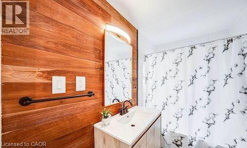 Wood-finish accent wall with integrated mirror and vanity lighting - 43 Adair Avenue S, Hamilton, ON - Indoor Photo Showing Bathroom
