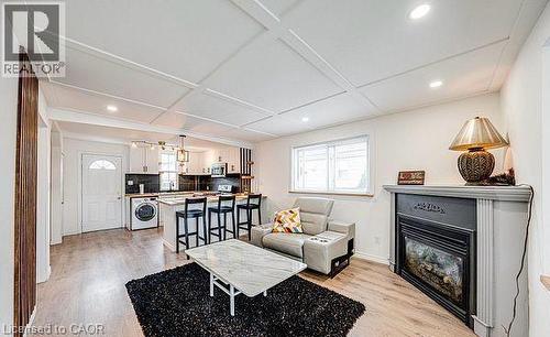 Open-concept living space featuring wood-finish flooring, a coffered ceiling with recessed lighting, and a built-in fireplace with a mantel - 43 Adair Avenue S, Hamilton, ON - Indoor Photo Showing Living Room With Fireplace