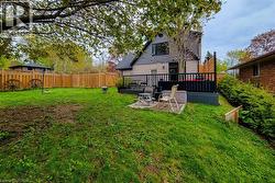 Expansive backyard featuring a wood fence, mature tree, and a multi-level deck with black railings - 