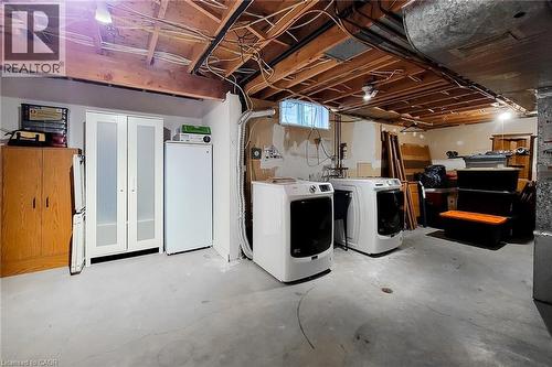 Basement laundry area featuring two front-loading machines, exposed ceiling joists, concrete flooring, and a small window - 49 Ashwood Drive, Cambridge, ON - Indoor Photo Showing Laundry Room