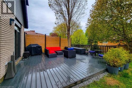 Expansive composite deck featuring a privacy fence, dark railing, mature trees, and a brick exterior - 49 Ashwood Drive, Cambridge, ON - Outdoor With Deck Patio Veranda