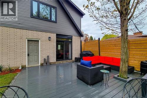 Spacious grey composite deck with an integrated tree planter, complemented by a horizontal wood privacy fence and a sliding glass door entry - 49 Ashwood Drive, Cambridge, ON - Outdoor With Deck Patio Veranda With Exterior