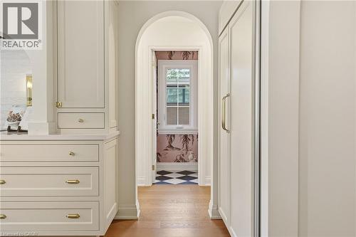 Archway entry with white trim, wood-finish flooring, built-in cabinetry with brass hardware, and a fully integrated appliance - 3081 Balmoral Avenue, Burlington, ON - Indoor Photo Showing Other Room