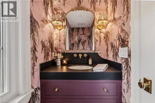 Vanity featuring a dark countertop with an integrated sink, wall-mounted faucet, and plum-colored cabinetry - 3081 Balmoral Avenue, Burlington, ON - Indoor Photo Showing Bathroom
