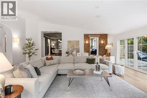 Spacious living area featuring light wood-finish flooring, a brick accent wall, and recessed ceiling lighting - 3081 Balmoral Avenue, Burlington, ON - Indoor Photo Showing Living Room