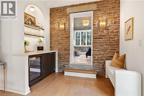 Hardwood flooring and exposed stone wall with sconce lighting - 3081 Balmoral Avenue, Burlington, ON - Indoor Photo Showing Other Room