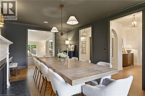 Spacious dining area featuring a light wood-finish table, recessed lighting, and a brass-tone chandelier - 3081 Balmoral Avenue, Burlington, ON - Indoor Photo Showing Dining Room With Fireplace
