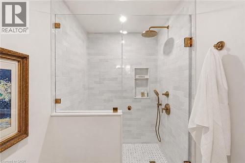 Enclosed shower featuring clear glass panels with brass-finish hardware, white subway tile walls, and a mosaic tile floor - 3081 Balmoral Avenue, Burlington, ON - Indoor Photo Showing Bathroom