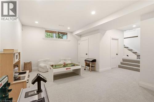 Carpeted lower-level room featuring recessed lighting, a window providing natural light, and access to a carpeted staircase - 3081 Balmoral Avenue, Burlington, ON - Indoor