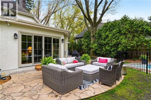 Flagstone patio featuring an exterior wall with multiple sliding glass doors, exterior wall sconces, and a black metal fence - 3081 Balmoral Avenue, Burlington, ON - Outdoor With Deck Patio Veranda
