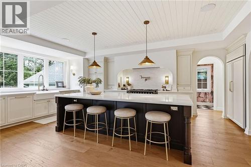 Kitchen featuring a large island with a light-colored countertop, recessed panel cabinetry, wood-finish flooring, a farmhouse sink, and a shiplap ceiling - 3081 Balmoral Avenue, Burlington, ON - Indoor Photo Showing Kitchen With Upgraded Kitchen