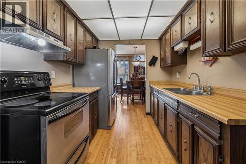 Galley kitchen featuring wood-finish flooring, dark wood cabinetry, and light wood-finish countertops - 21 Lionshead Lookout, Brampton, ON - Indoor Photo Showing Kitchen With Double Sink