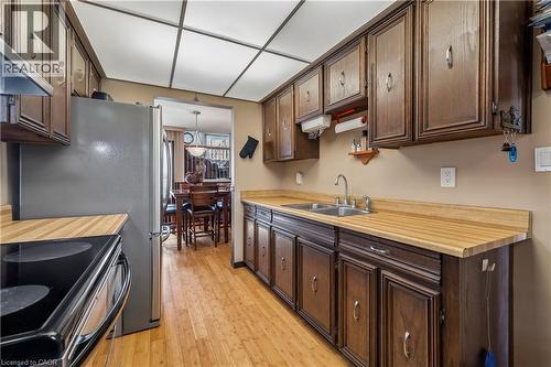 Kitchen featuring wood-finish flooring, dark wood cabinetry, light wood-finish countertops, and a double basin stainless steel sink - 21 Lionshead Lookout, Brampton, ON - Indoor Photo Showing Kitchen With Double Sink