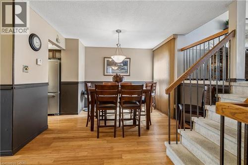 Dining area featuring wood-finish flooring, two-tone wall treatment, and a hanging pendant light fixture - 21 Lionshead Lookout, Brampton, ON - Indoor Photo Showing Dining Room