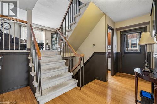 Entryway featuring wood-finish flooring, a carpeted staircase with wood handrails and metal balusters, and wainscoting - 21 Lionshead Lookout, Brampton, ON - Indoor Photo Showing Other Room
