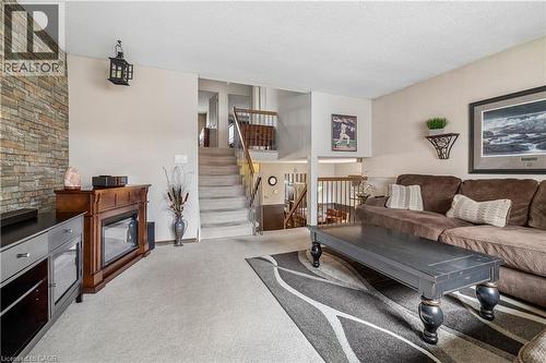 Multi-level living space featuring neutral carpeting, a stone accent wall, and wood balusters - 21 Lionshead Lookout, Brampton, ON - Indoor Photo Showing Living Room
