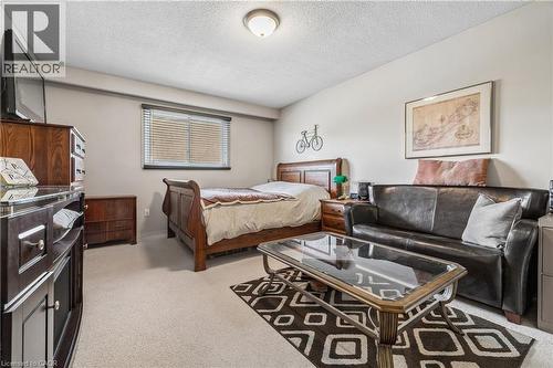Carpeted bedroom area featuring a window with blinds, a dark wood-finish bed frame, and a leather-finish sofa - 21 Lionshead Lookout, Brampton, ON - Indoor Photo Showing Bedroom
