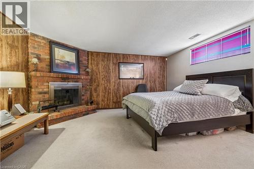 Brick fireplace with a metal insert and hearth, complemented by wood-panel accent walls - 21 Lionshead Lookout, Brampton, ON - Indoor Photo Showing Bedroom With Fireplace