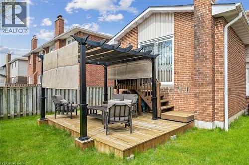 Backyard featuring a wood-finish deck with a black pergola, steps to a sliding glass door, and a brick exterior - 21 Lionshead Lookout, Brampton, ON - Outdoor With Deck Patio Veranda With Exterior