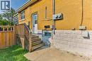 Yellow brick exterior with a white entry door, wood privacy fence, and concrete patio - 38 Dunkirk Drive Unit# B, Hamilton, ON  - Outdoor With Exterior 