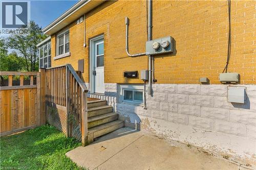 Yellow brick exterior with a white entry door, wood privacy fence, and concrete patio - 38 Dunkirk Drive Unit# B, Hamilton, ON - Outdoor With Exterior