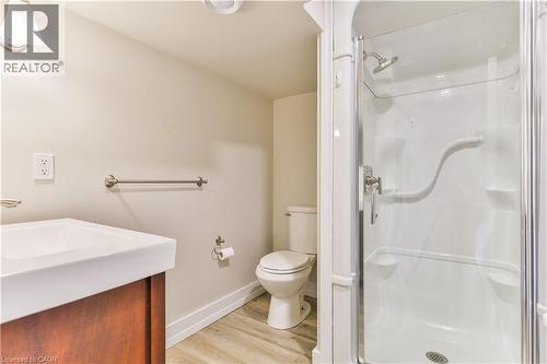 Compact bathroom featuring a glass-enclosed shower, single vanity with integrated sink, wood-finish cabinetry, and neutral wall tones - 38 Dunkirk Drive Unit# B, Hamilton, ON - Indoor Photo Showing Bathroom