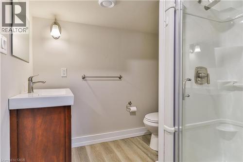 Three-piece bathroom featuring a corner vanity with a rectangular basin, glass-enclosed shower, wood-finish flooring, and a recessed ceiling light - 38 Dunkirk Drive Unit# B, Hamilton, ON - Indoor Photo Showing Bathroom