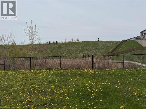 Expansive green space featuring a chain-link fence, a sloped grassy hill, and distant residential structures - 63 Ridge Road Unit# Upper, Cambridge, ON - Outdoor