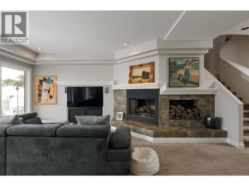 Lower Level Living Room walk out to covered terrace and pool - 228 Caliburn Court, Kelowna, BC - Indoor Photo Showing Living Room With Fireplace