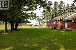 Expansive green lawn with mature trees bordering a brick exterior - 