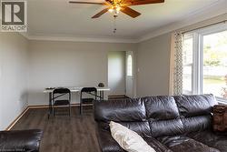 Living area featuring wood-finish flooring, a ceiling fan with light fixture, and a white entry door with decorative glass - 