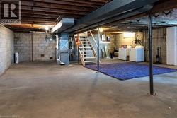 Unfinished basement featuring concrete block walls, exposed wood ceiling joists, and a concrete floor - 