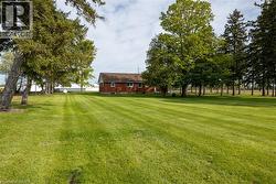 Expansive green lawn with visible mowing stripes, bordered by mature trees - 