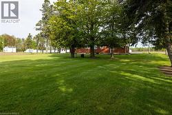 Expansive green lawn with mature shade trees providing natural canopy - 