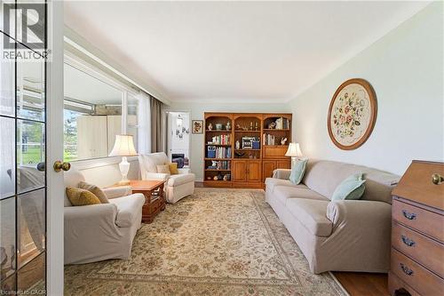 Living area featuring a built-in wood bookshelf with integrated cabinetry, an ornate area rug, and a large window providing natural light - 10 Huisman Lane, Hamilton, ON 