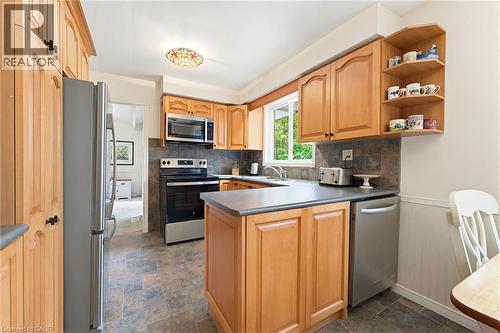 Kitchen featuring light wood cabinetry, stainless steel appliances, dark countertop surfaces, and a tiled backsplash - 10 Huisman Lane, Hamilton, ON 