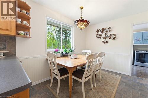 Dining area featuring a window overlooking greenery, wood-finish flooring, wainscoting, and a decorative overhead light fixture - 10 Huisman Lane, Hamilton, ON 