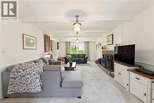 Spacious living area featuring exposed ceiling beams, two pendant light fixtures, and light-colored carpeting - 10 Huisman Lane, Hamilton, ON 