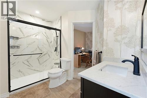 Ensuite Bathroom featuring a shower with a sliding glass enclosure, white marble-look wall tiles, and black fixtures - 10 Huisman Lane, Hamilton, ON 
