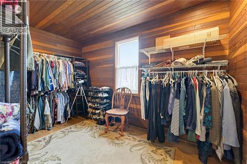 Spacious room featuring wood-finish walls and ceiling, ample natural light from a single window, extensive wire shelving, and multiple clothing rods for storage - 10 Huisman Lane, Hamilton, ON 