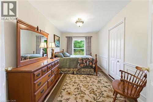 Bedroom featuring wood-finish flooring, a window with curtains, and a ceiling-mounted light fixture - 10 Huisman Lane, Hamilton, ON 