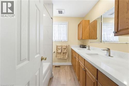 Bathroom featuring a double vanity with integrated sinks, light wood cabinetry, and brushed nickel fixtures - 10 Huisman Lane, Hamilton, ON 