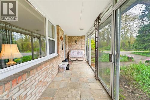 Enclosed porch featuring a brick half-wall, large windows, sliding glass doors, and tiled flooring - 10 Huisman Lane, Hamilton, ON 