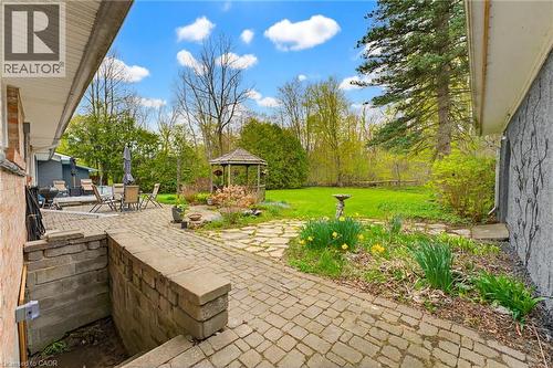 Expansive outdoor living area featuring a large paver patio, a stone path, a built-in stone retaining wall, and a wood gazebo - 10 Huisman Lane, Hamilton, ON 