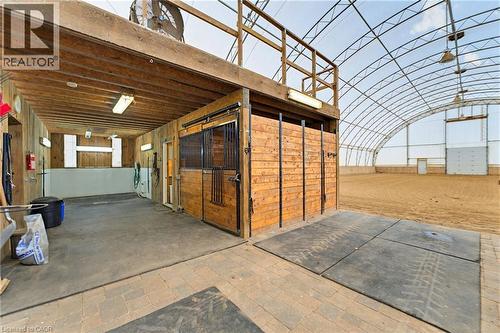 Indoor riding arena featuring a sand surface, arched metal frame, and overhead lighting, direct access to 4 box stalls - 10 Huisman Lane, Hamilton, ON 