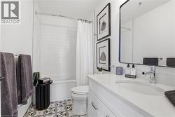 Bathroom featuring a white vanity with an integrated sink and chrome fixtures, framed by a rectangular mirror - 