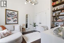 Bright interior space featuring high ceilings, dark wood-finish flooring, white walls, built-in shelving, and white double doors with matte black hardware - 