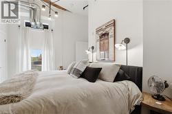 Bedroom featuring high ceilings, exposed ductwork, and a ceiling fan with integrated lighting - 