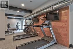 Fitness center with wood-paneled accent wall, exposed ductwork, recessed lighting, and mirrored wall - 