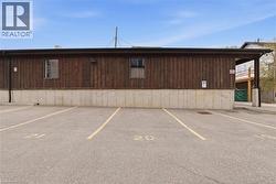 Paved parking area featuring striped parking spaces and a wood-sided structure with a concrete foundation - 